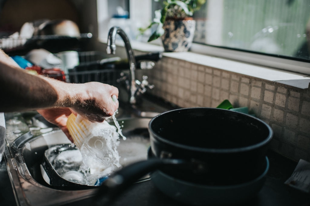 Man-washing-dishes-at-a-sink